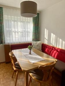 comedor con mesa y sofá rojo en Appartements Wieseneck - beste Lage inklusive Sommercard, en Ramsau am Dachstein