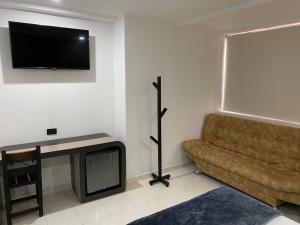 sala de estar con sofá y TV de pantalla plana en Hotel Plaza Real Ocaña, en Ocaña