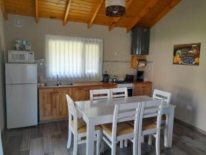 a kitchen with a white table and chairs and a white refrigerator at Cabañas La Lucía in Villa Ventana