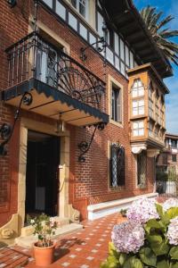a brick building with a balcony and some flowers at Villa colonial Jardin Algorta centro Puerto Viejo in Getxo