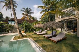 ośrodek z basenem z krzesłami i palmami w obiekcie Tao House Jungle Boutique Villas w mieście Ahangama