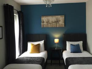 two beds in a room with blue walls at The Rooms at The Spout in Kilcullen