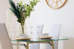 a glass table with a vase of flowers in a dining room at DELUXE Tranquil Central 2 Bedroom Home-Free Parking, WIFI, Garden Views, University of Birmingham, Botanical Gardens, Edgbaston cricket in Birmingham