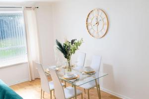 uma mesa de jantar com cadeiras e um relógio na parede em DELUXE Tranquil Central 2 Bedroom Home-Free Parking, WIFI, Garden Views, University of Birmingham, Botanical Gardens, Edgbaston cricket em Birmingham