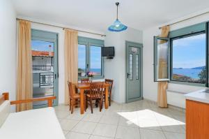 - un salon avec une table, des chaises et des fenêtres dans l'établissement Apartments Exadas, à Chrysi Ammoudia