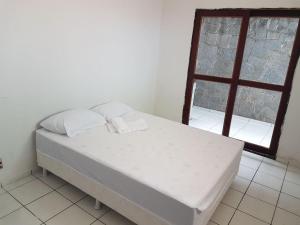 a bed with two pillows in a room with a window at Residencial Candelária in Natal
