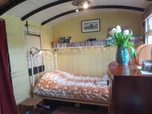 ein Schlafzimmer mit einem Bett und einer Blumenvase auf einer Kommode in der Unterkunft Sundial Cottage in Norwich