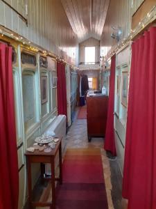 a corridor of a train with red curtains and a table at Sundial Cottage in Norwich