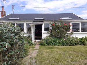 a white house with red flowers in the yard at Sundial Cottage in Norwich