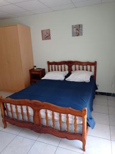 a bedroom with a large wooden bed with a blue blanket at Villa NORICA in Bordezac
