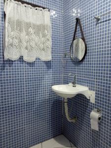 a blue tiled bathroom with a sink and a mirror at Casa da Fê in São Sebastião