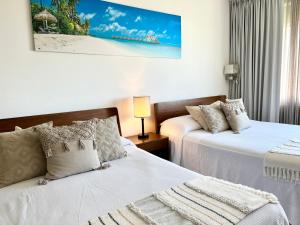 a bedroom with two beds and a picture of a beach at Xcanan Loft On Park Royal, the best area in Cancún right on the beach in Cancún