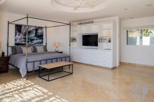 Dormitorio con cama con dosel y TV. en Stunning 6bd Villa in Palmilla! Fully Staffed w Chauffeur and Yacht included!, en San José del Cabo
