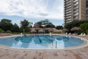 una gran piscina con sillas y un edificio en Beach Apartment Jacuzzi Wifi in Santa Marta by Huespedia 402, en Santa Marta