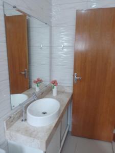 een badkamer met een wastafel en een grote spiegel bij Casa em Caraguatatuba Praia Massaguaçu/Cocanha in Caraguatatuba