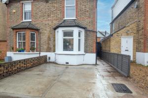 uma entrada vazia em frente a um edifício de tijolos em Lovely 4 Bedroom London Home with Free Parking, Garden, WiFi By Roost Accommodation em Kingston upon Thames