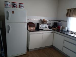 uma cozinha com armários brancos e um frigorífico branco em La Fermina em Villa Giardino