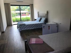 a room with two beds and a refrigerator and a window at Espaço Casa na Rocha in São José dos Campos