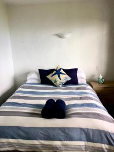 Cama con sábanas y almohadas de rayas azules y blancas en 90 Mile Paradise Ahipara en Ahipara