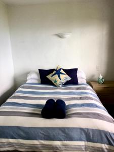 a bed with blue and white striped sheets and pillows at 90 Mile Paradise Ahipara in Ahipara