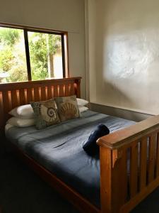 a bedroom with a wooden bed with a window at 90 Mile Paradise Ahipara in Ahipara
