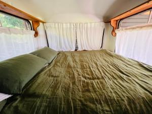 a bed in an rv with two windows at Mesa Bus - Deluxe Byron Hinterland Eco Stay in Rosebank