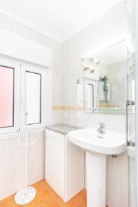a white bathroom with a sink and a mirror at De la cama a la mar in Luanco