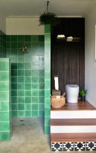 uma casa de banho com paredes em azulejo verde e uma banheira em Mesa Bus - Deluxe Byron Hinterland Eco Stay em Rosebank