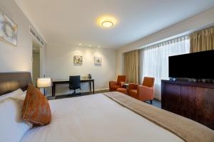 a hotel room with a bed and a flat screen tv at Hotel Grand Chancellor Adelaide in Adelaide