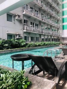 a swimming pool with a table and chairs next to a building at Deluxe 1 Bedroom with Balcony Condotel in Green Residences Malate Manila near MOA and Airport in Manila