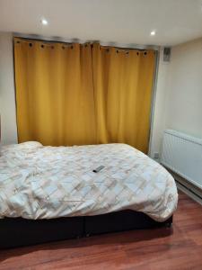 a bed in a bedroom with a yellow curtain at Relevant properties in Welling