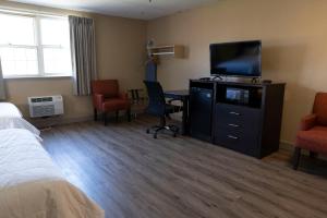 a hotel room with a television and a desk with chairs at Framingham Inn in Framingham