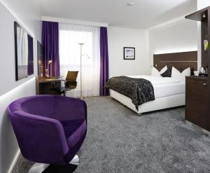 a hotel room with a bed and a purple chair at Central Hotel in Villingen-Schwenningen