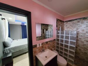 a bathroom with pink walls and a sink and a bed at Sunset Bay House in Six Huts