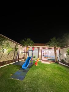 a playground with a slide in a yard at night at شاليه فاملي دي family day in Hail