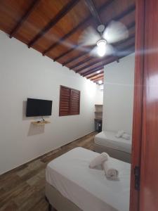 a bedroom with two beds and a ceiling fan at Casa Bete e Farouk in São Miguel do Gostoso