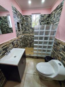 La salle de bains est pourvue de toilettes blanches et d'un lavabo. dans l'établissement Sunset Bay House, à Six Huts