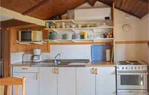 Nice Home In Ronneby With Kitchen في رونيبي: مطبخ بدولاب بيضاء ومغسلة وموقد