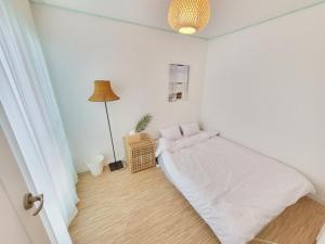 a white bedroom with a bed and a lamp at Eeumgil in Daegu