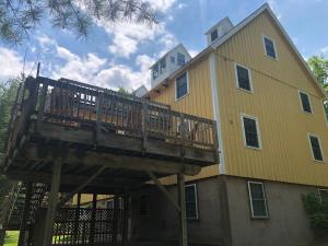 a large yellow house with a wooden deck at Yellow Barn Estate in Freeville