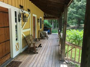 um alpendre de madeira com um banco numa casa em Yellow Barn Estate em Freeville