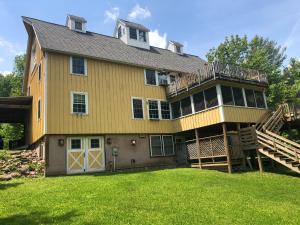 a large house with a porch and a deck at Yellow Barn Estate in Freeville