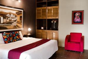 una camera con un grande letto e una sedia rossa di Hotel Los Olivos Santiago Atitlan a Santiago Atitlán