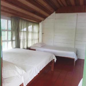 twee bedden in een kamer met een raam bij Hotel Lomas del Paiyü in Puerto Nariño