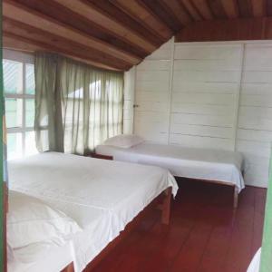 two beds in a room with a window at Hotel Lomas del Paiyü in Puerto Nariño
