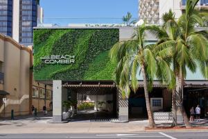 ホノルルにあるOUTRIGGER Waikiki Beachcomber Hotelのヤシの木が茂る緑の壁の建物