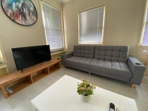 a living room with a couch and a flat screen tv at Melbourne Mitcham Holiday Home in Mitcham