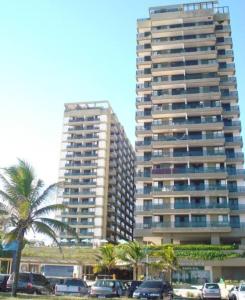 two tall buildings with cars parked in a parking lot at Apartamento com toda infra e em frente a praia in Rio de Janeiro