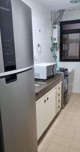 a kitchen with a refrigerator and a microwave at Apartamento com toda infra e em frente a praia in Rio de Janeiro