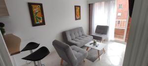 a living room with chairs and a couch and a table at Hermoso Apartamento Ubicado en Zona Céntrica de Medellín in Medellín